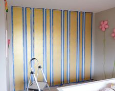 a bathroom with yellow and blue stripes painted on the wall next to a bathtub