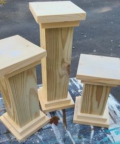 three wooden pedestals sitting on top of a blue tarp next to each other