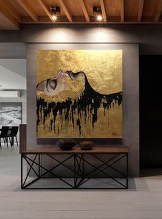 a large painting hanging on the wall above a table in front of a dining room