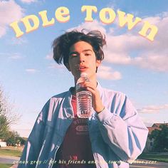 a young man holding a water bottle while standing in front of a sign that says idle town