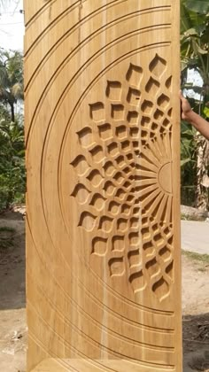 a person standing next to a large wooden object with carvings on it's sides