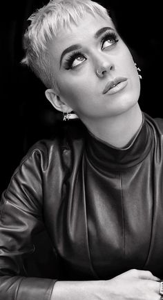 a black and white photo of a woman with short hair wearing a leather jacket looking at the camera