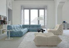 a living room filled with lots of furniture and white carpeted flooring on top of a hard wood floor