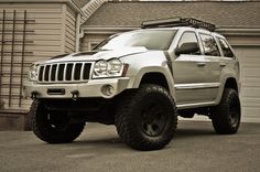 a jeep parked in front of a house with a roof rack on it's side