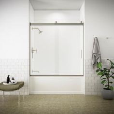 a bathroom with white tile walls and flooring has a glass shower door on the wall