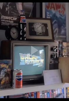 an old tv sitting on top of a book shelf next to a can of soda