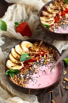 two bowls filled with fruit and granola on top of a table