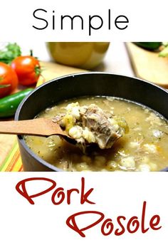 a bowl of pork posole soup with a wooden spoon in it and tomatoes on the side