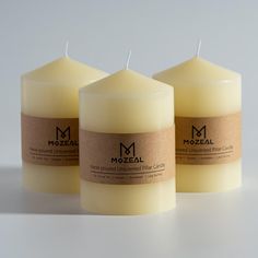 three candles with labels on them sitting side by side in front of a white background