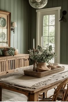 a dining room with green walls and wooden table in front of the window, surrounded by wicker chairs