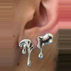 a close up of a person's ear with two silver earrings on top of it