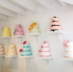 many different colored cakes on shelves in a room