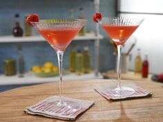 two martini glasses sitting on top of a wooden table