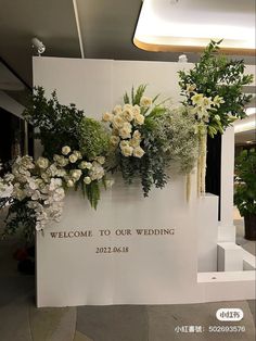 a welcome sign with flowers and greenery on it