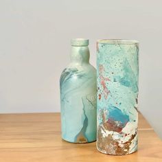 two vases sitting on top of a wooden table next to each other, one blue and the other green