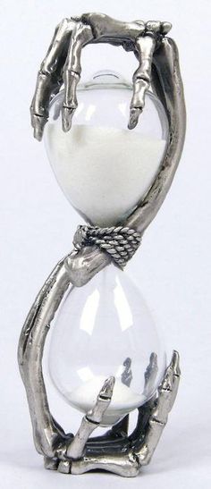 an hourglass sitting on top of a white table next to a pair of hands