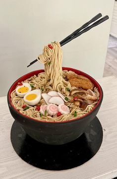 a bowl filled with noodles, meats and eggs on top of a wooden table