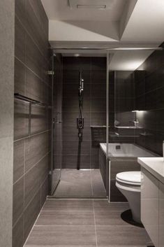 a bathroom with a toilet, sink, and shower stall in black and white colors