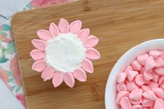 a bowl of marshmallows next to a cupcake on a cutting board