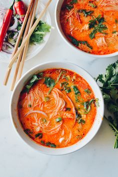 two bowls of soup with chopsticks on the side