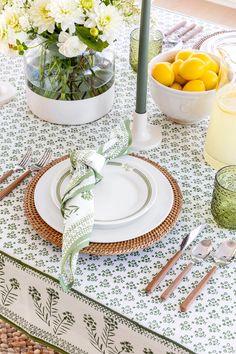 the table is set with plates, silverware and flowers in vases on it