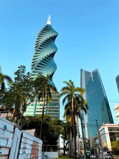 an unusual building in the middle of a city with palm trees and tall buildings behind it