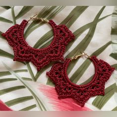 two pairs of red crocheted hoop earrings on top of a white and green cloth