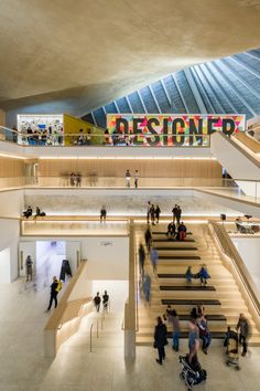 people are walking up and down the stairs in an open area with a sign that reads designer