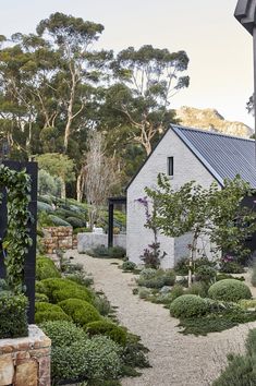 an outdoor garden with gravel path leading to a white brick building surrounded by greenery