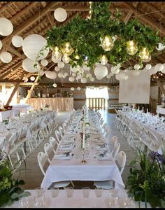 tables and chairs are set up with white linens, greenery and paper lanterns