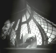 a black and white photo of a person holding a camera in front of a lamp