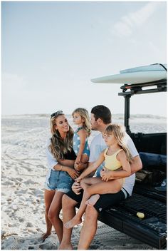 a family sitting on the back of a truck at the beach