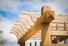 a wooden structure with several pieces of wood attached to the top and bottom, against a cloudy blue sky