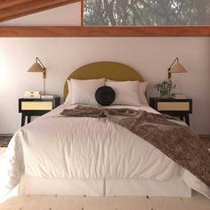 a bed with white sheets and pillows in a bedroom