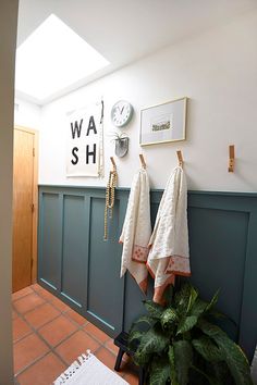 a bathroom with two towels hanging on the wall and a potted plant next to it