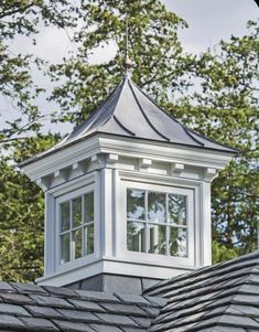 a white cupola on the roof of a house with trees in the back ground