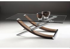 a glass table with two cups on it and a wooden stand in front of it