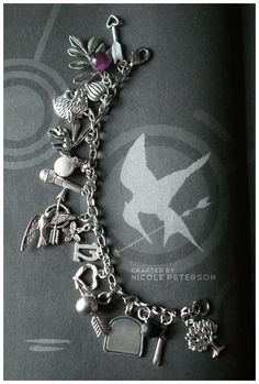 a bracelet with charms on it sitting on top of a black book cover in the shape of a bird