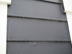 the side of a building with some black shingles on it