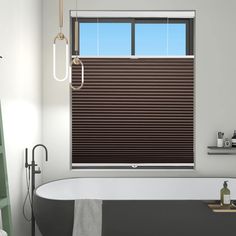 a bath room with a tub and a window that has blinds on the windowsill