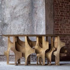 a wooden table sitting in front of a brick wall next to a cement wall with an abstract design on it