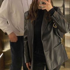 a woman taking a selfie in front of an elevator while holding a cell phone