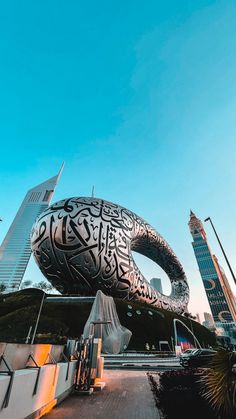 an elephant sculpture in the middle of a city with tall buildings behind it and blue sky