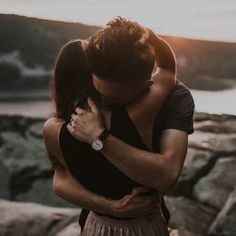 a man and woman embracing in front of the ocean