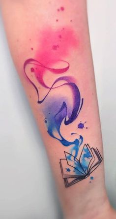 a colorful tattoo on the arm of a woman with an open book in her hand