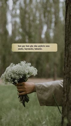 a person holding a bouquet of flowers in front of a tree with a quote above it