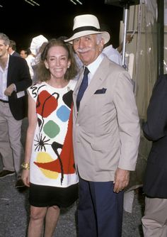 an older man and woman standing next to each other in front of a group of people