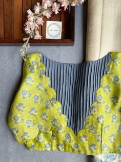 a yellow and blue dress with flowers on it next to a wooden clock, window sill