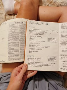 a person laying down reading a book on top of a bed with their legs crossed