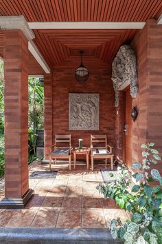 an outdoor covered patio with wooden chairs and table in the middle, surrounded by greenery